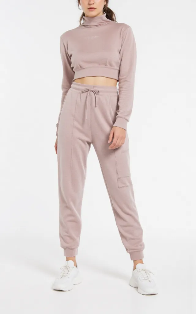 A French female model wearing Athleisure   style clothing, against a white background, in a front   facing shot focusing on shoes